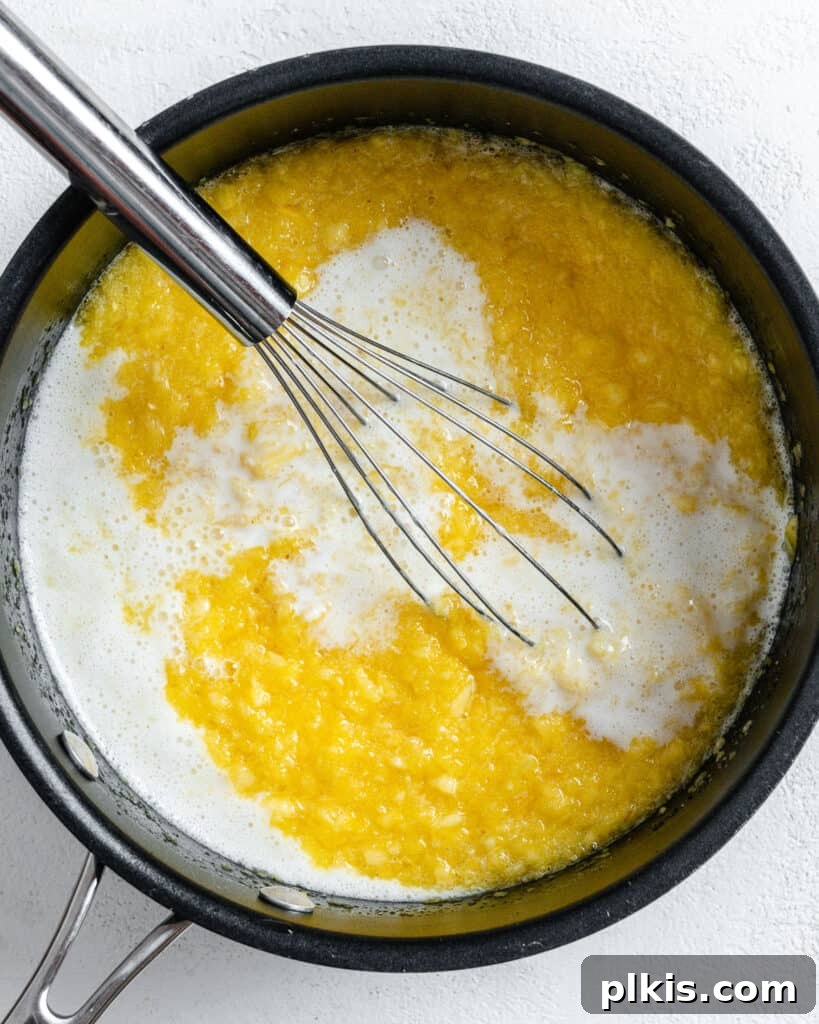 Tropical Vegan Coconut Pineapple Pie 8 Process shot of the pineapple pie filling being stirred in a black saucepan on the stove, showing its thickening texture.