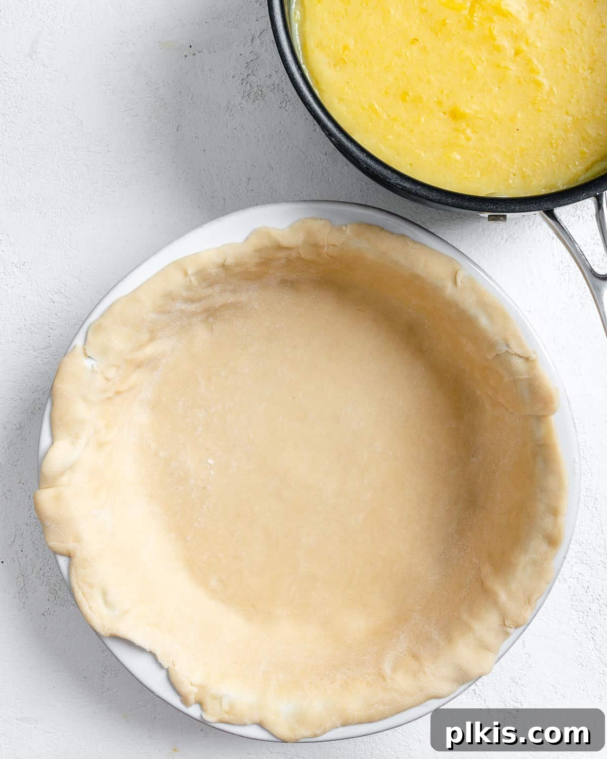Tropical Vegan Coconut Pineapple Pie 9 A premade pie crust neatly settled into a pie mold, ready for filling, against a clean white background.