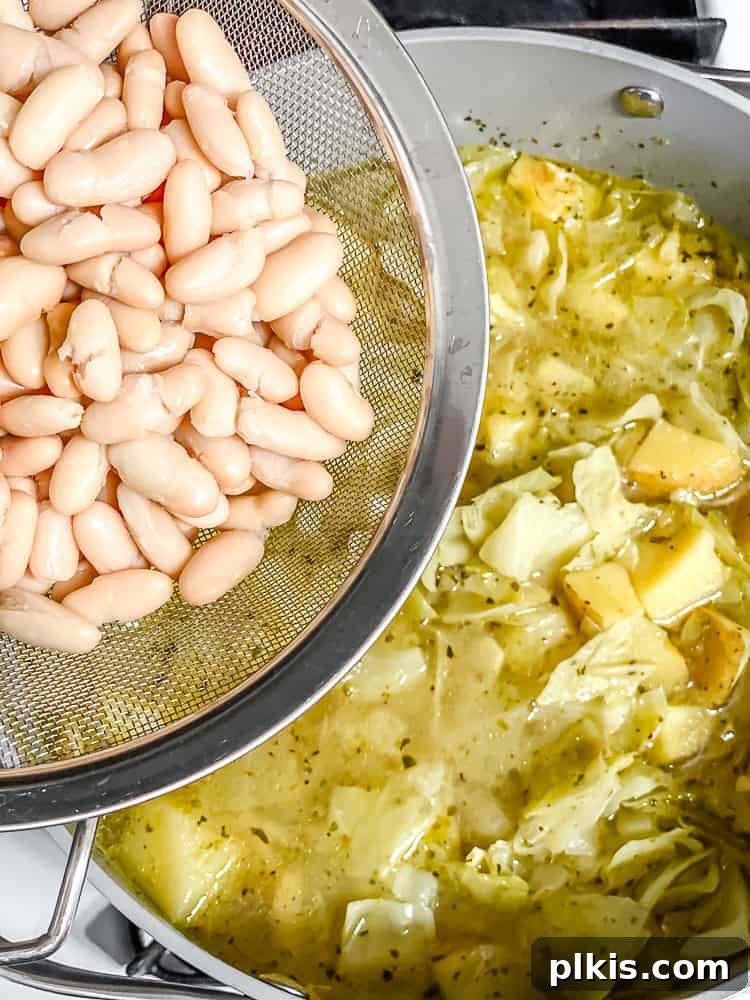 Rustic Cabbage and Bean Pot 7 Process shot of cooked cannellini beans being added to the simmering Cabbage Bean Soup.