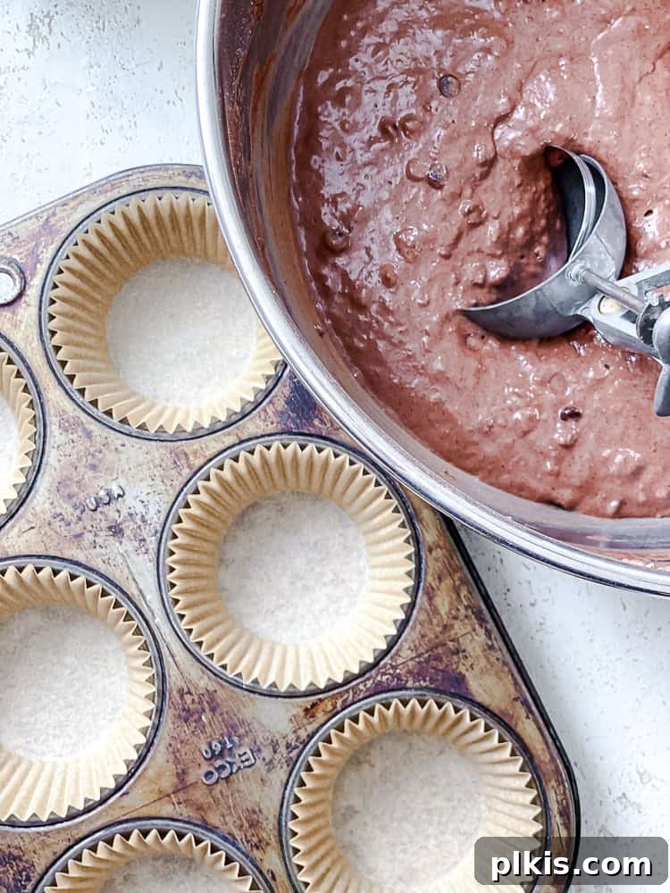 Decadent Double Chocolate Muffins 7 Process shot demonstrating how to add muffin batter into a lined muffin tin.