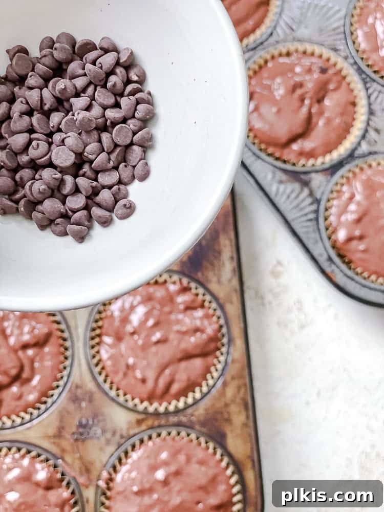 Decadent Double Chocolate Muffins 8 Process shot showing additional chocolate chips being sprinkled on top of the muffin batter in the tin.
