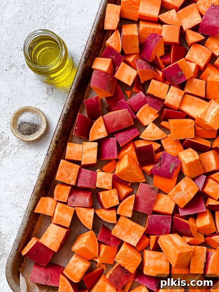 Warm Roasted Sweet Potato Salad 4 Cubed sweet potatoes seasoned with olive oil, salt, and pepper, spread out on a baking sheet, ready for the oven.
