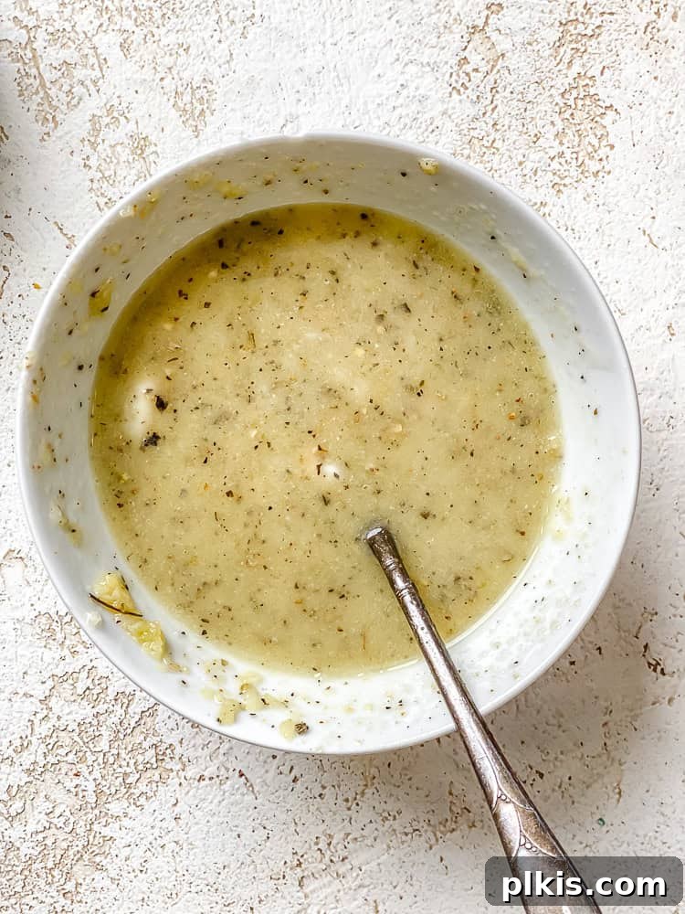 Effortless Plant-Based Garlic Bread 6 A process shot showing the creamy mixture of melted vegan butter, garlic, olive oil, and Italian seasoning in a bowl, ready to be spread.
