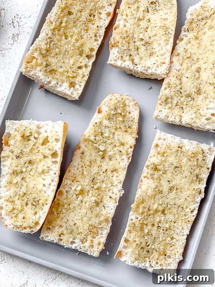 Effortless Plant-Based Garlic Bread 8 Several slices of vegan garlic bread, generously coated with the butter mixture, arranged on a baking sheet, ready for the oven.