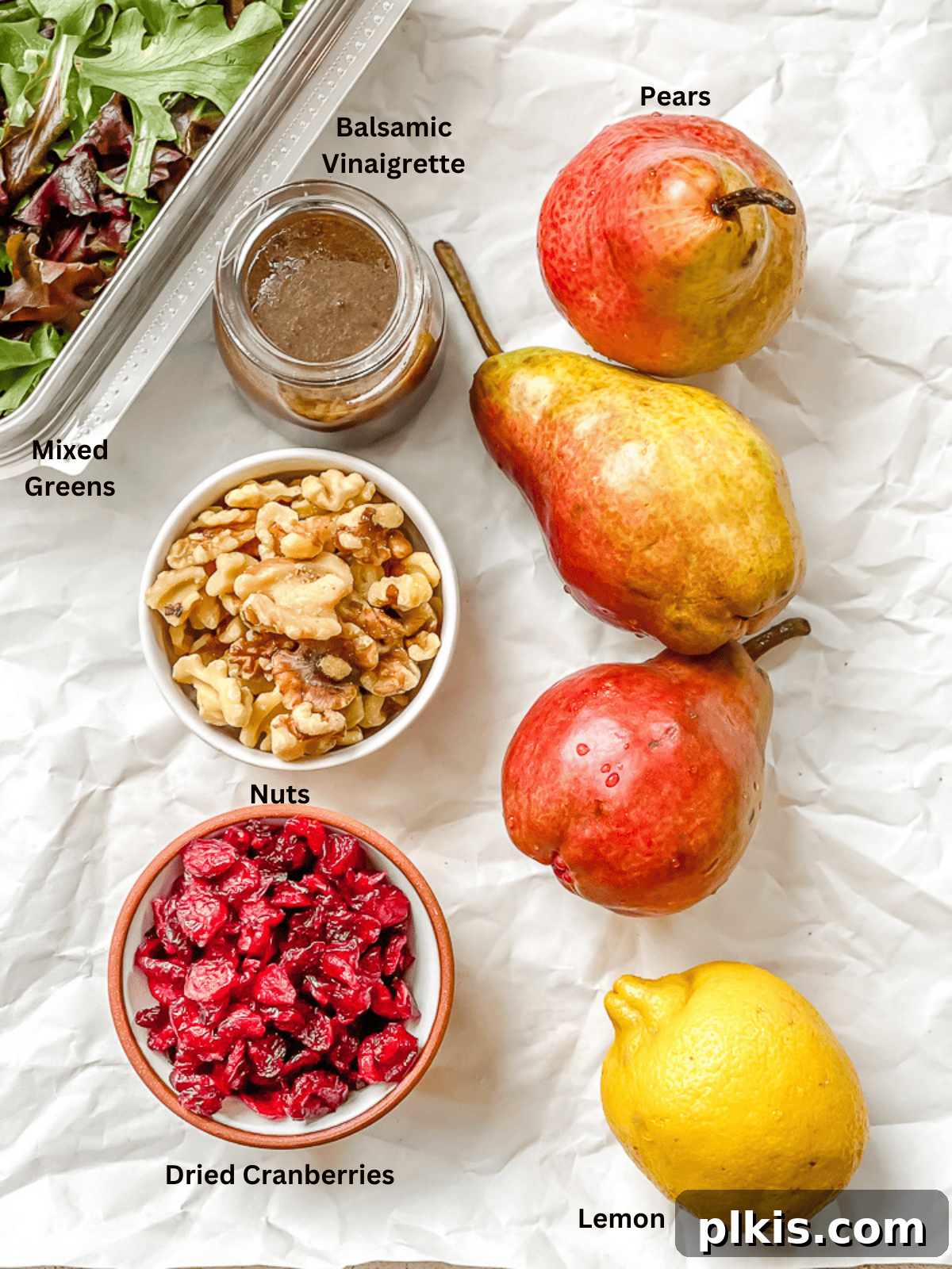Harvest Pear and Gorgonzola Salad 3 Individual ingredients for pear salad laid out with labels, including mixed greens, sliced pears, lemon, dried cranberries, nuts, and balsamic vinaigrette.