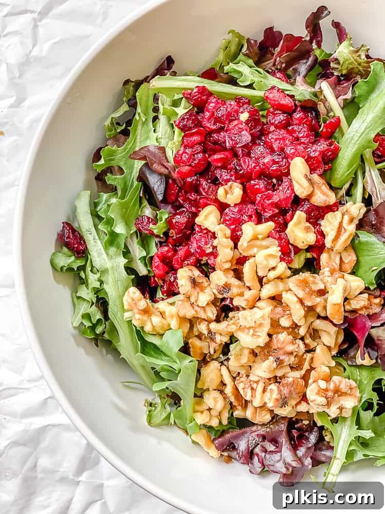 Harvest Pear and Gorgonzola Salad 5 A large bowl contains mixed greens, dried cranberries, and nuts, ready for the next ingredients of the pear salad.