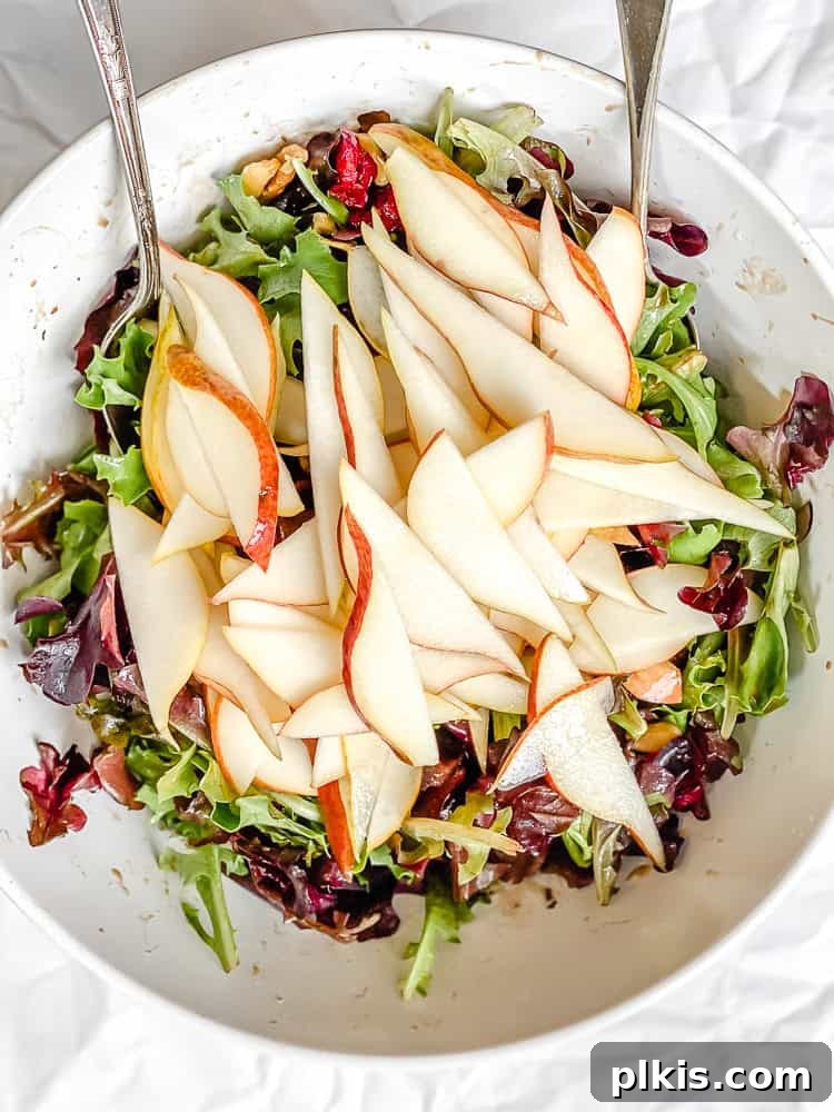 Harvest Pear and Gorgonzola Salad 7 A finished pear salad is garnished with a drizzle of dressing and a light sprinkle of salt, ready to be served.