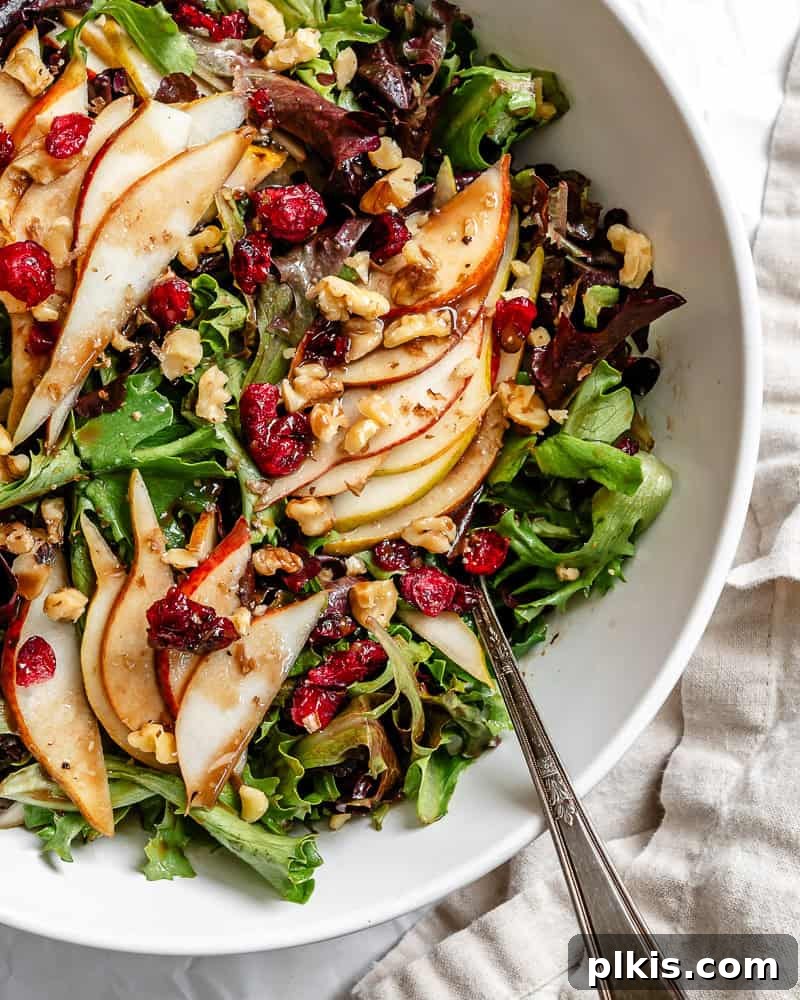 Harvest Pear and Gorgonzola Salad 8 A close-up view of a perfectly arranged pear salad in a large bowl, highlighting the texture of the pears, greens, nuts, and cranberries.