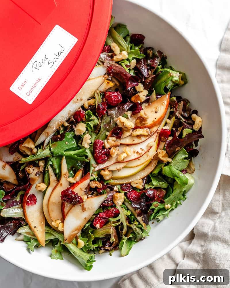 Harvest Pear and Gorgonzola Salad 9 A large, clear storage container filled with the mixed components of a pear salad, suitable for meal prep or storing leftovers.