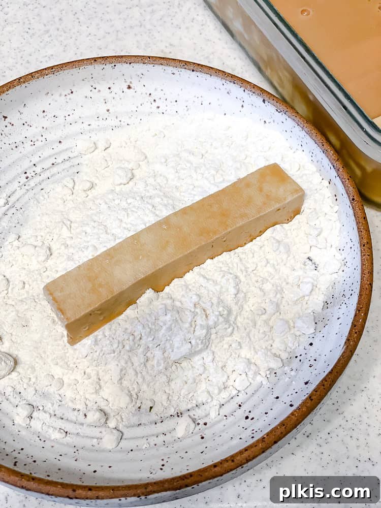 Crispy Vegan Fish Fingers 7 Process shot showing a tofu stick being coated in the flour mixture.