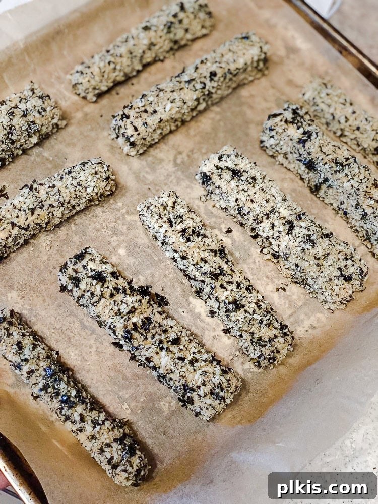 Crispy Vegan Fish Fingers 8 Process shot showing breaded tofu fish sticks arranged on a parchment-lined baking sheet, ready for the oven.