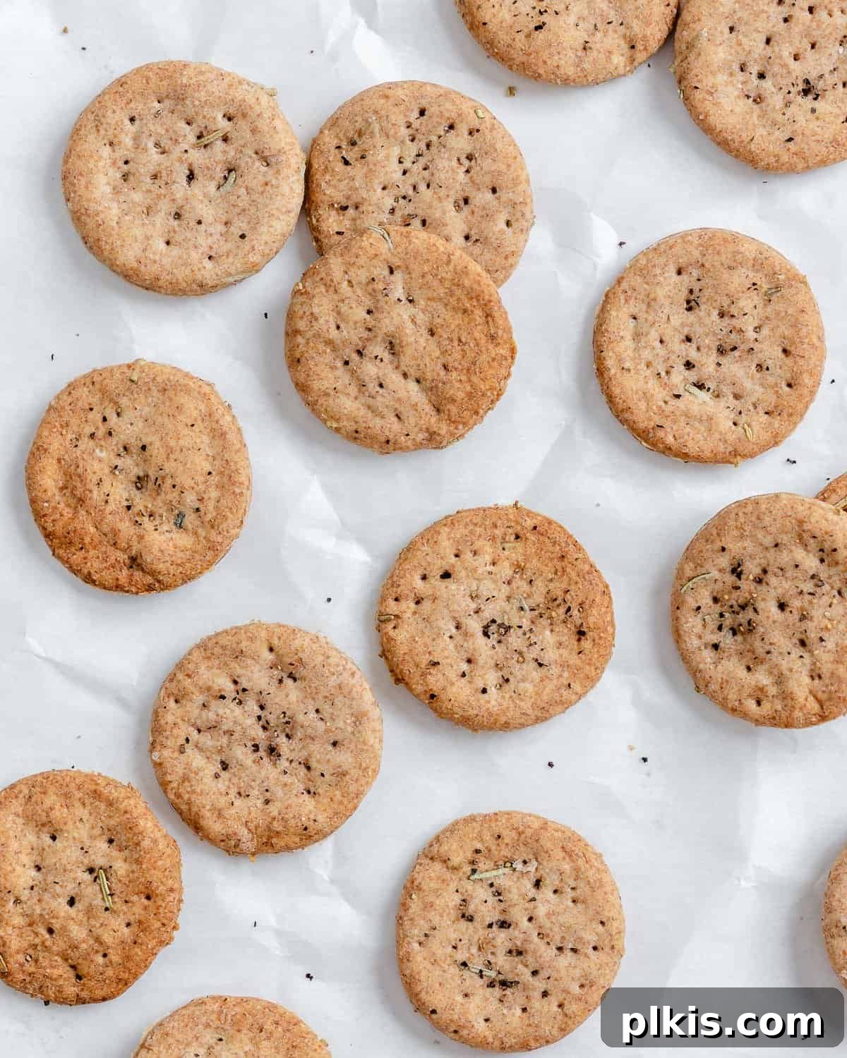 Rustic Rosemary Vegan Crisps 2 Crispy homemade Rosemary Vegan Crackers scattered on a white surface, ready to be enjoyed.
