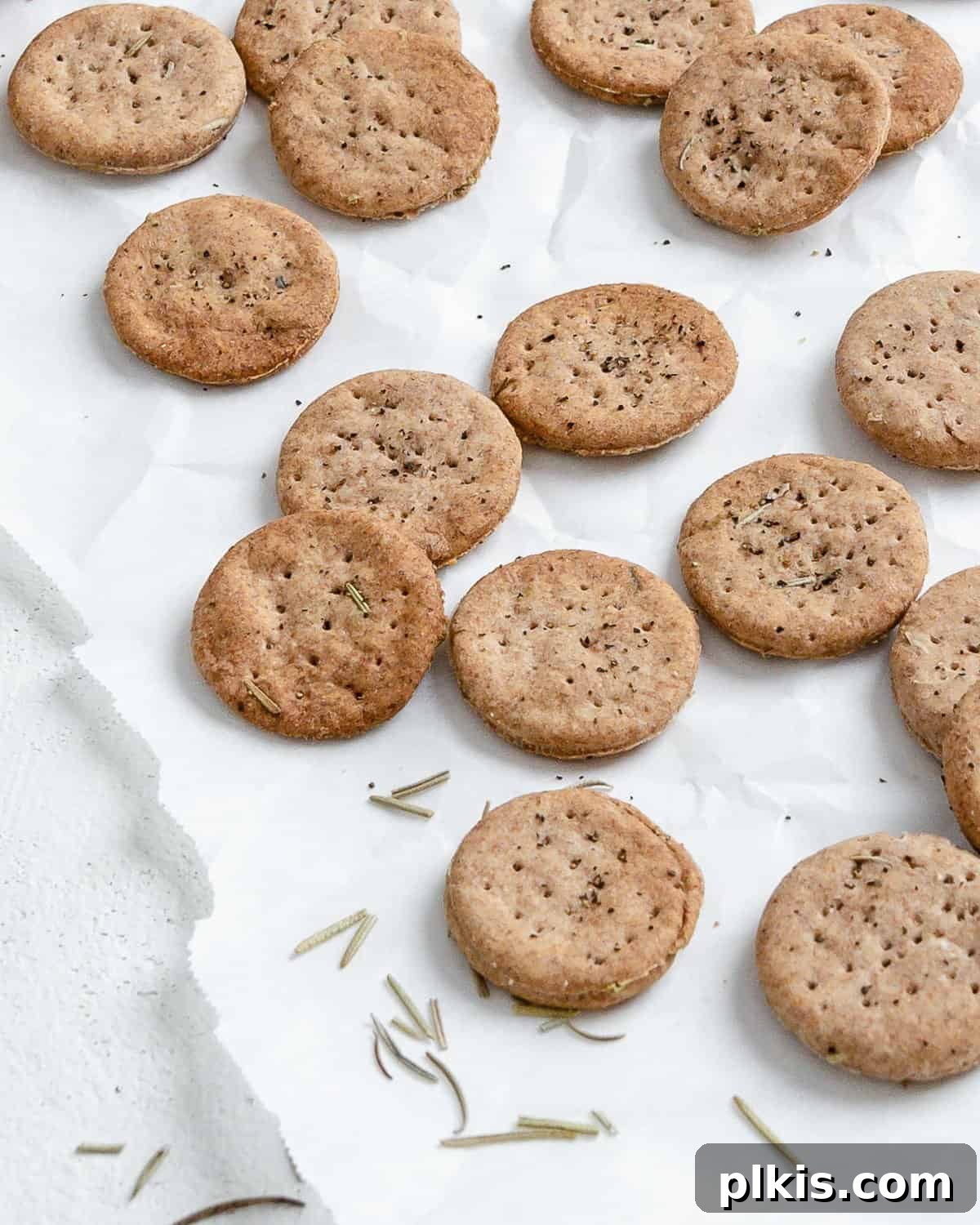Rustic Rosemary Vegan Crisps 11 More completed Rosemary Vegan Crackers scattered enticingly on a white surface.