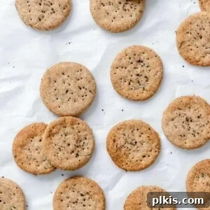 Rustic Rosemary Vegan Crisps 12 Completed Rosemary Vegan Crackers scattered on a white surface, presented for the recipe card.