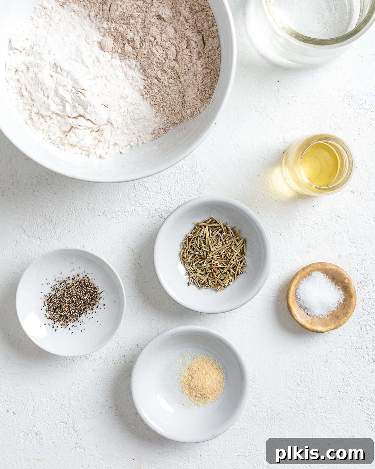 Rustic Rosemary Vegan Crisps 3 Ingredients for Rosemary Vegan Crackers neatly arranged in small white bowls on a pristine white surface.