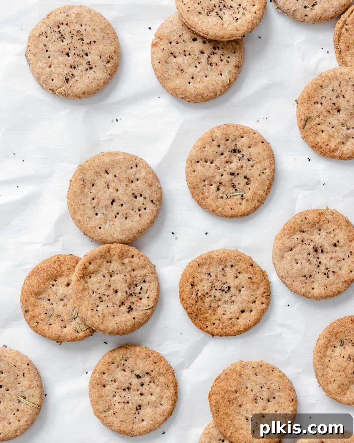 Rustic Rosemary Vegan Crisps 10 A fresh batch of completed Rosemary Vegan Crackers beautifully scattered on a white surface.