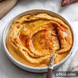 A bowl of vibrant orange sweet potato hummus, perfect for dipping.