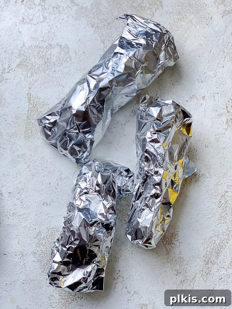 Golden Sweet Potato Hummus 4 Three sweet potatoes individually wrapped in aluminum foil, ready for roasting.
