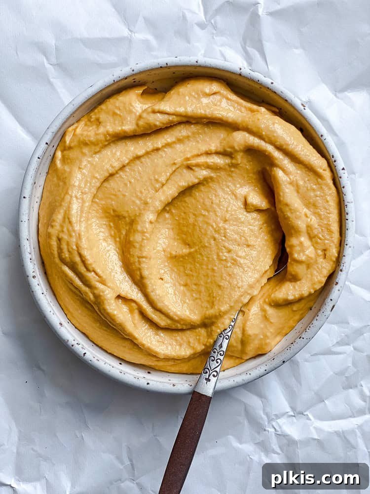 Golden Sweet Potato Hummus 10 A beautifully swirled bowl of sweet potato hummus, ready to be served, garnished with a sprinkle of paprika and a drizzle of olive oil.