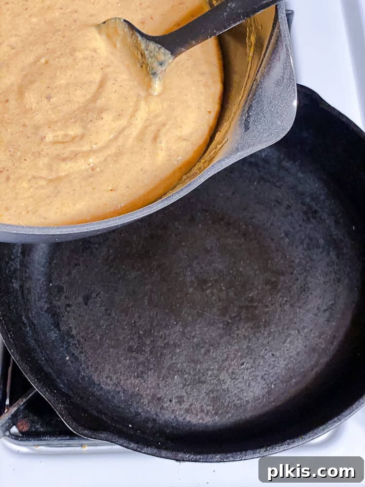 Spiced Sweet Potato Cornbread 8 Cornbread batter being poured from a bowl into a hot, oiled cast-iron skillet.