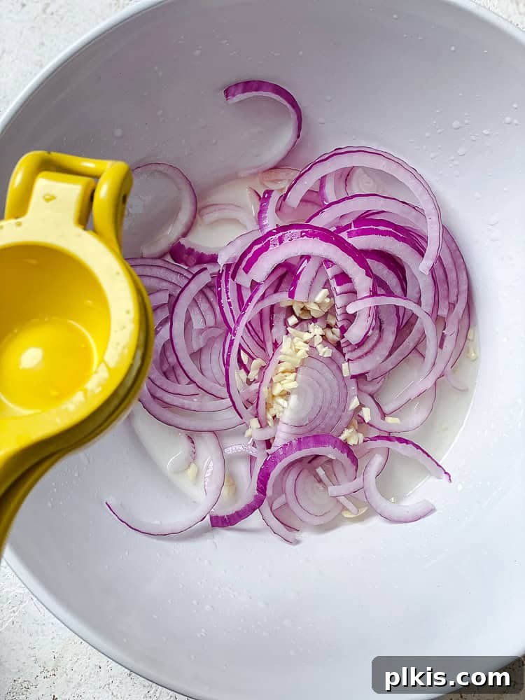 Zesty Green Bean Salad 5 process shot showing adding lemon juice to a bowl of onion and garlic