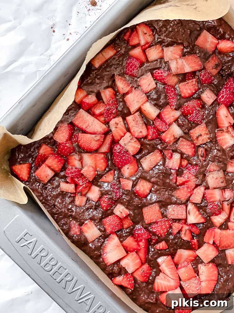 Strawberry Kissed Brownies 7 Process shot showing fresh strawberries added to the brownie batter in the baking pan.