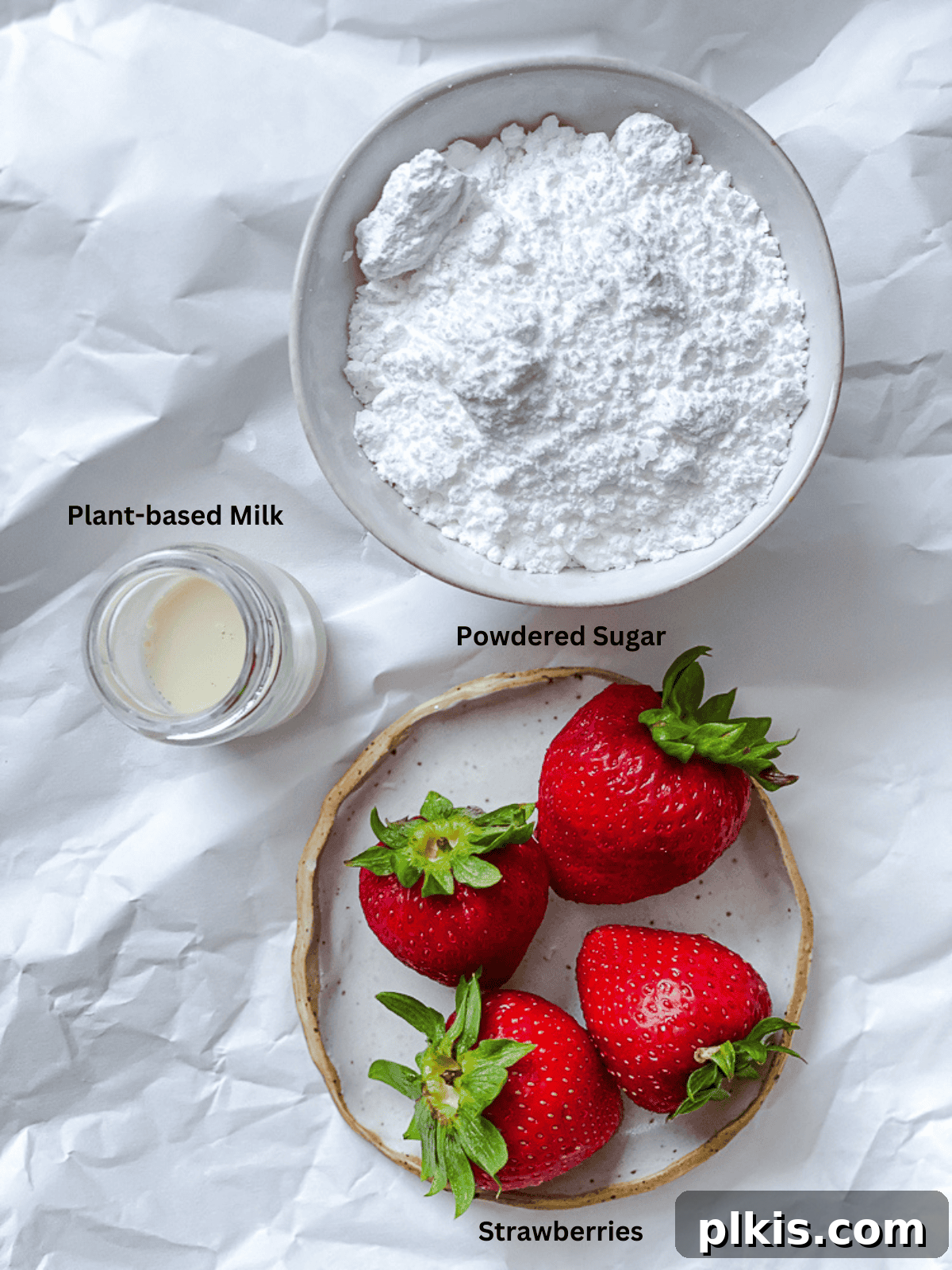 Effortless Strawberry Glaze for All Your Sweet Treats 3 Ingredients for Easy Strawberry Glaze laid out on a white surface, including strawberries, powdered sugar, and plant-based milk.