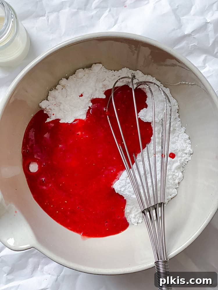 Effortless Strawberry Glaze for All Your Sweet Treats 5 A process shot showing powdered sugar being whisked into the strawberry puree in a bowl.