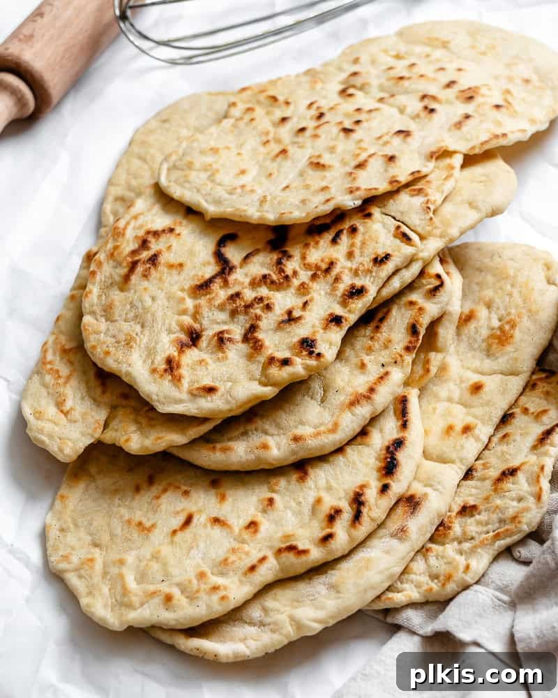 Fluffy Vegan Naan 2 A generous pile of homemade vegan naan, golden and lightly charred, ready to be enjoyed with a delicious meal.
