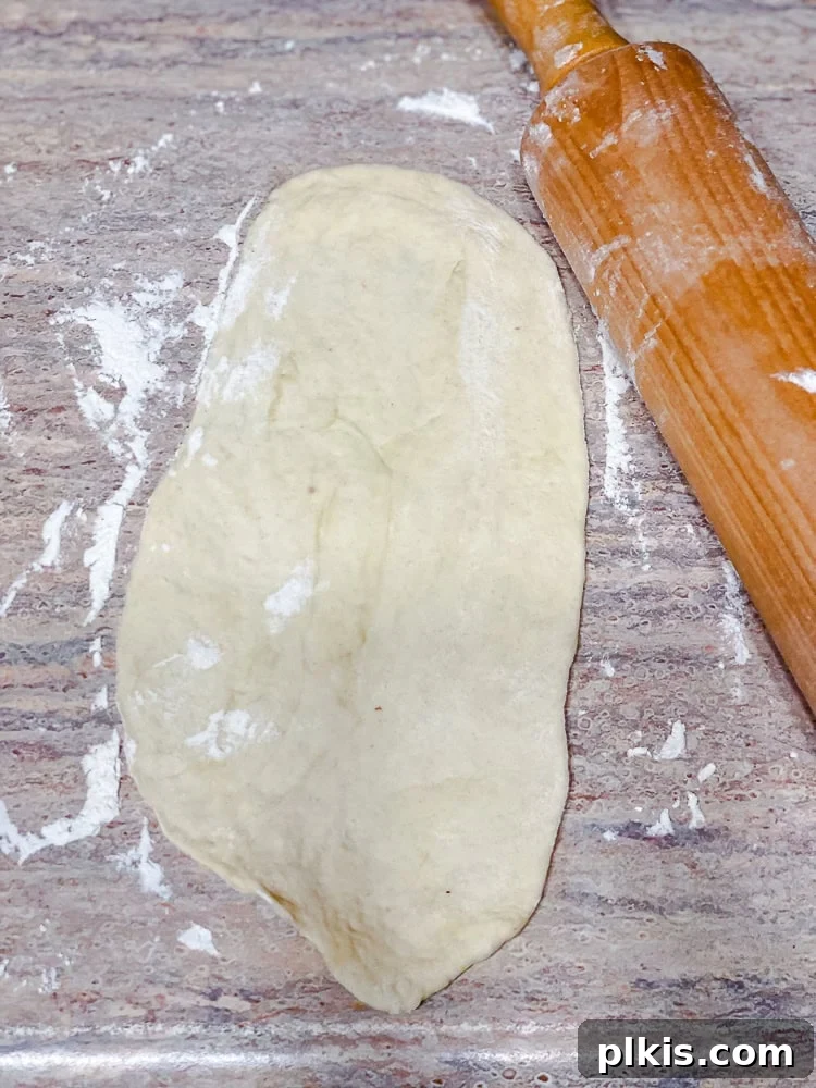 Fluffy Vegan Naan 13 A rolling pin skillfully flattening a piece of vegan naan dough on a floured surface.