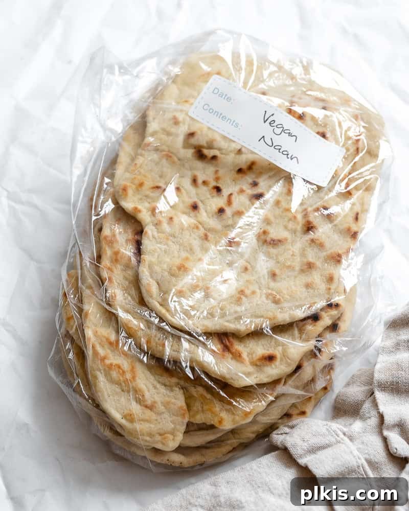 Fluffy Vegan Naan 15 A stack of freshly made vegan naan pieces, neatly wrapped in plastic for storage, showcasing their soft texture.