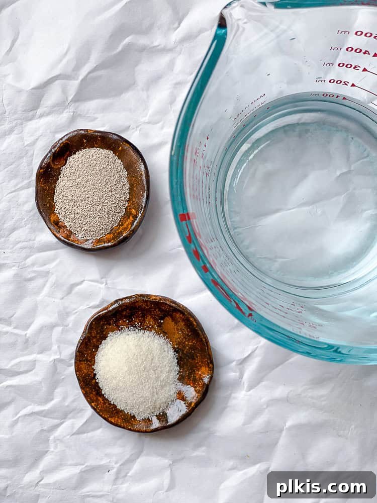 Fluffy Vegan Naan 4 Small bowls of yeast and sugar next to a glass of warm water, preparing for blooming.