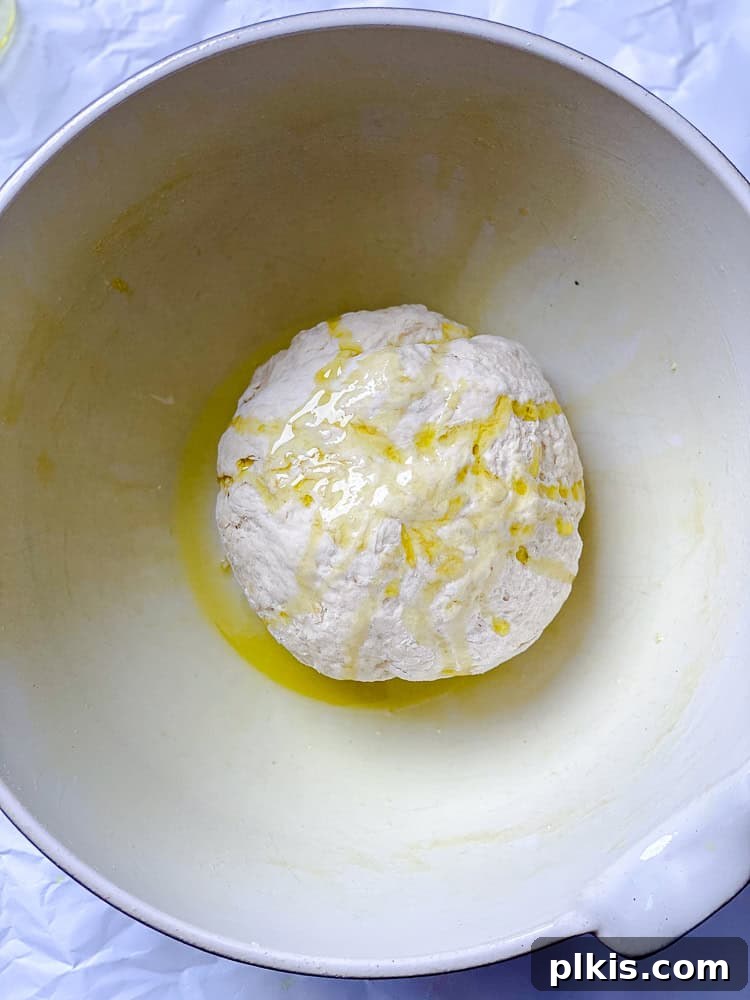 Fluffy Vegan Naan 10 A smooth ball of vegan naan dough nestled in an oiled bowl, covered and ready for rising.