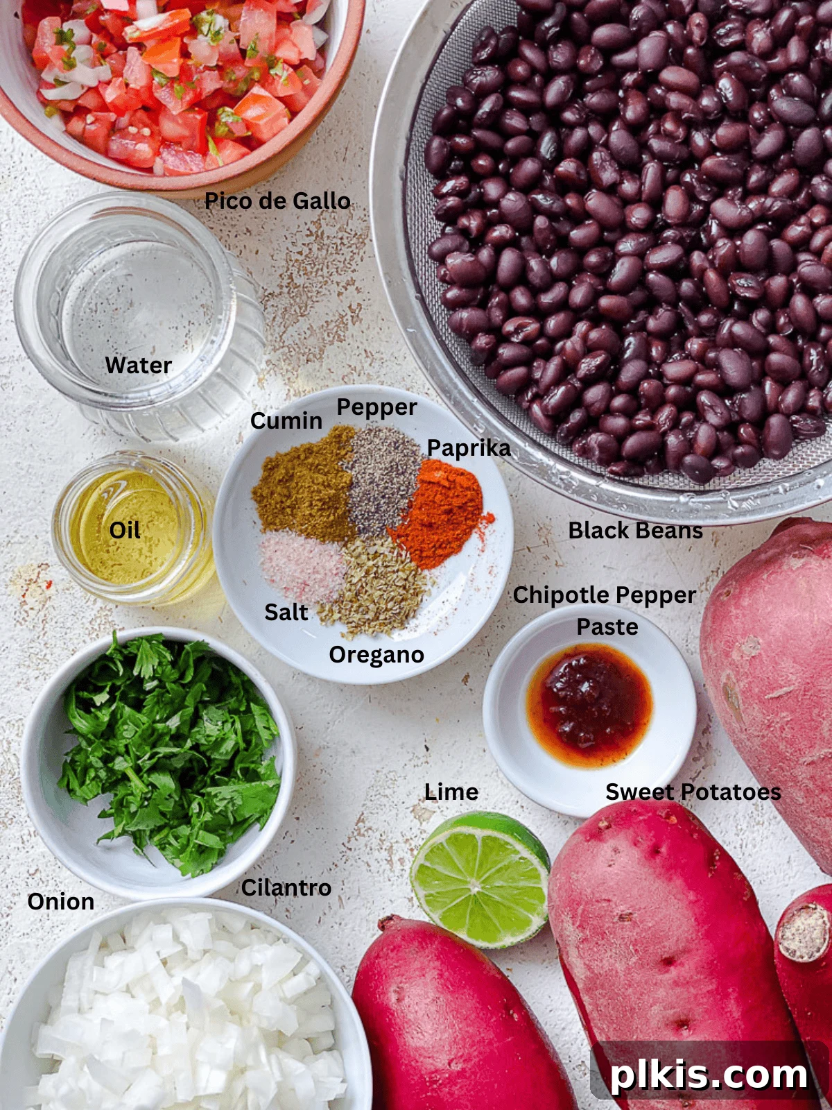 Hearty Sweet Potato Black Bean Tacos 3 A selection of fresh ingredients for Sweet Potato and Black Bean Tacos, including whole sweet potatoes, canned black beans, onions, and various spices, laid out on a clean white surface.