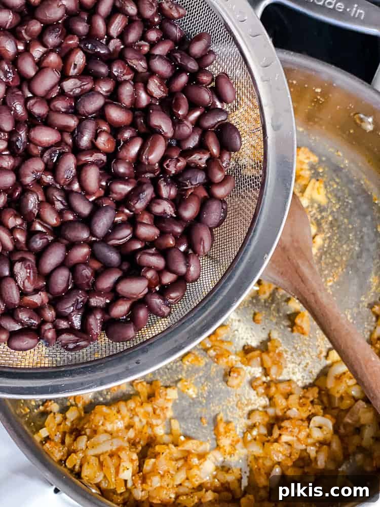 Hearty Sweet Potato Black Bean Tacos 6 Seasoned black beans simmering in a saucepan with a lid, creating a rich and flavorful filling.
