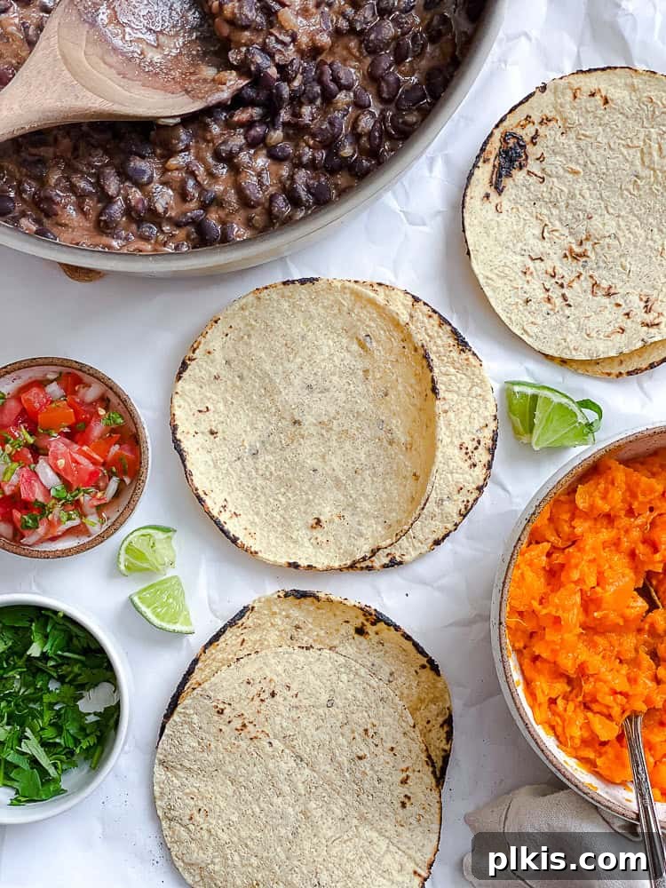 Hearty Sweet Potato Black Bean Tacos 8 A freshly assembled Sweet Potato and Black Bean Taco with generous fillings, pico de gallo, and cilantro, served with a lime wedge.