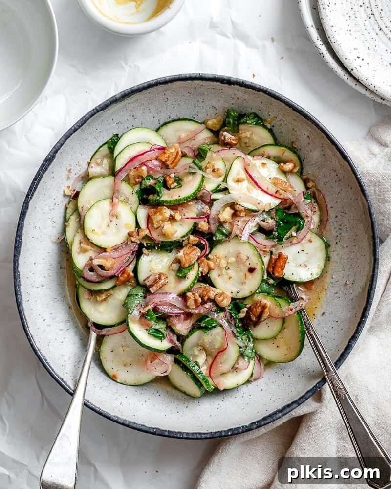 Zesty Zucchini Salad 2 A vibrant raw zucchini salad served in a elegant white bowl, garnished with fresh basil leaves.