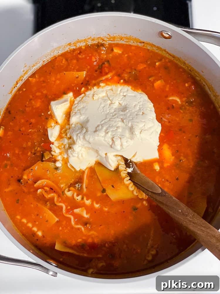 Tuscan Vegan Lasagna Soup 11 A wooden spoon gently stirring a block of silken tofu into the pot of vegan lasagna soup.