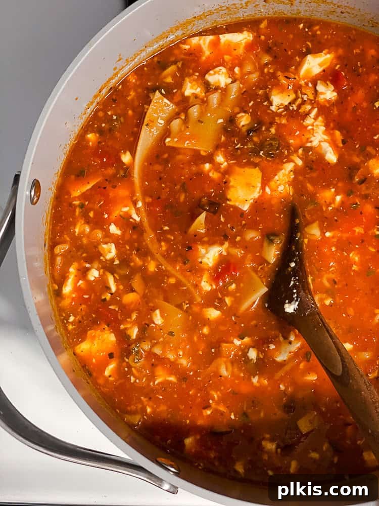 Tuscan Vegan Lasagna Soup 12 A wooden spoon stirring a pot of creamy vegan lasagna soup, showing the rich texture.