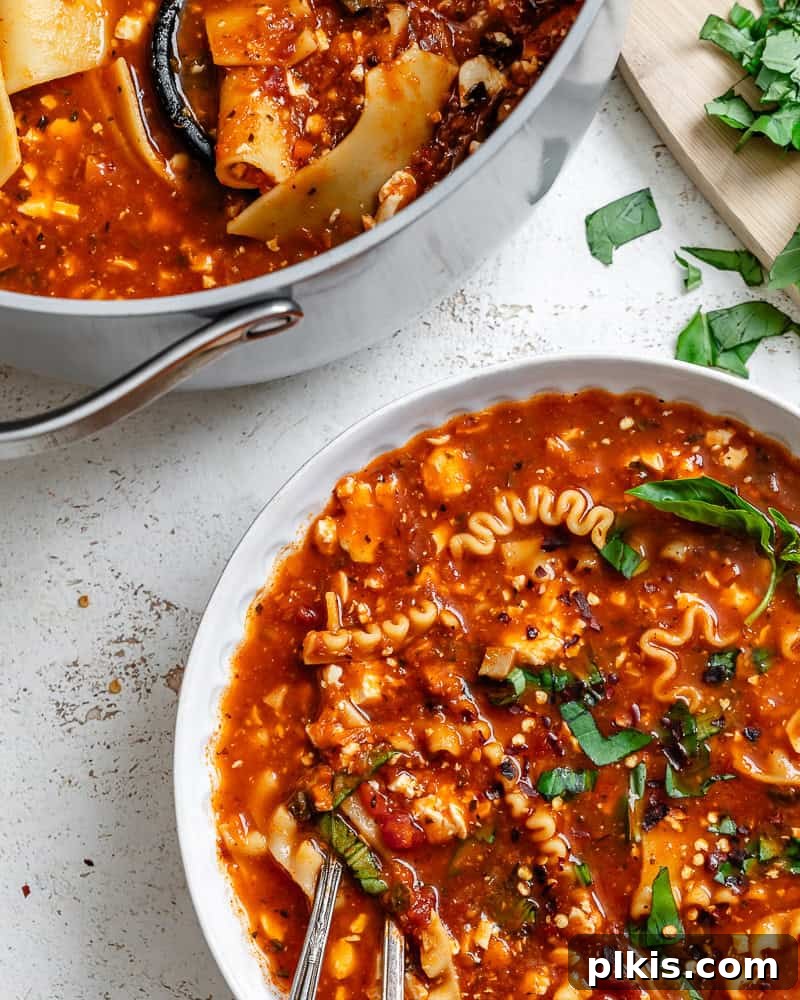 Tuscan Vegan Lasagna Soup 13 A single bowl of vegan lasagna soup, rich and creamy, next to a large pot of the soup, highlighting its comforting appeal.