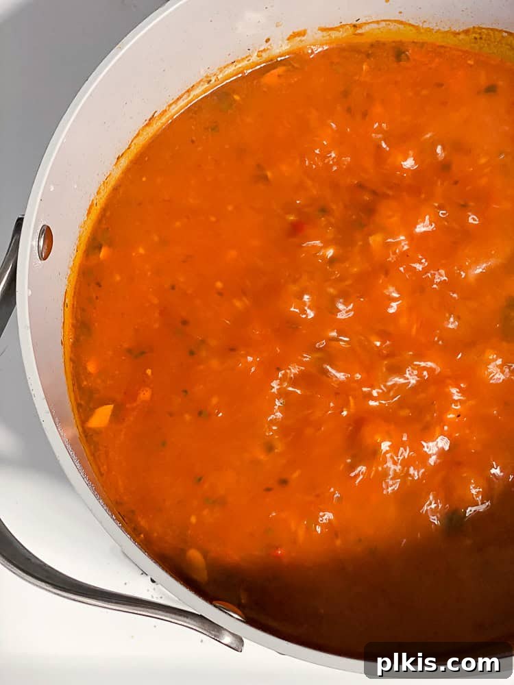 Tuscan Vegan Lasagna Soup 9 A large pot of vegan lasagna soup simmering gently, with bubbles rising to the surface.