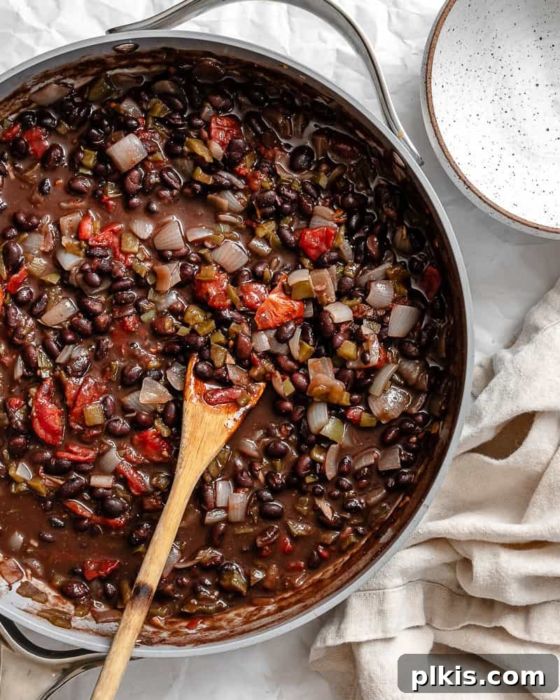 A large pot filled with steaming, rich black bean chili, ready to be served.