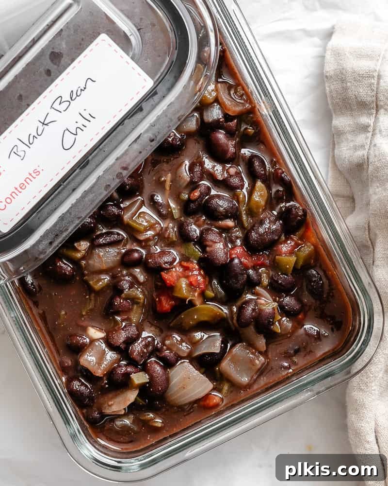A clear glass storage container filled with prepared black bean chili, ready for meal prep.