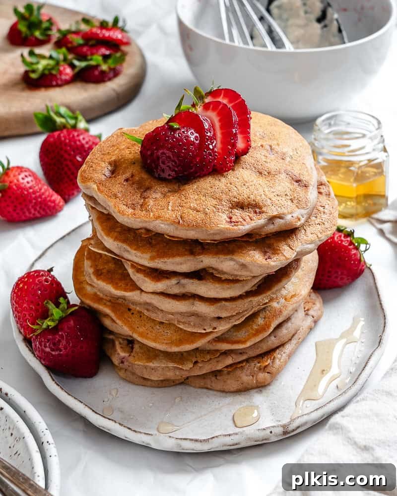 completed Strawberry Pancakes [Eggless & Dairy-Free] plated with fresh strawberries and syrup
