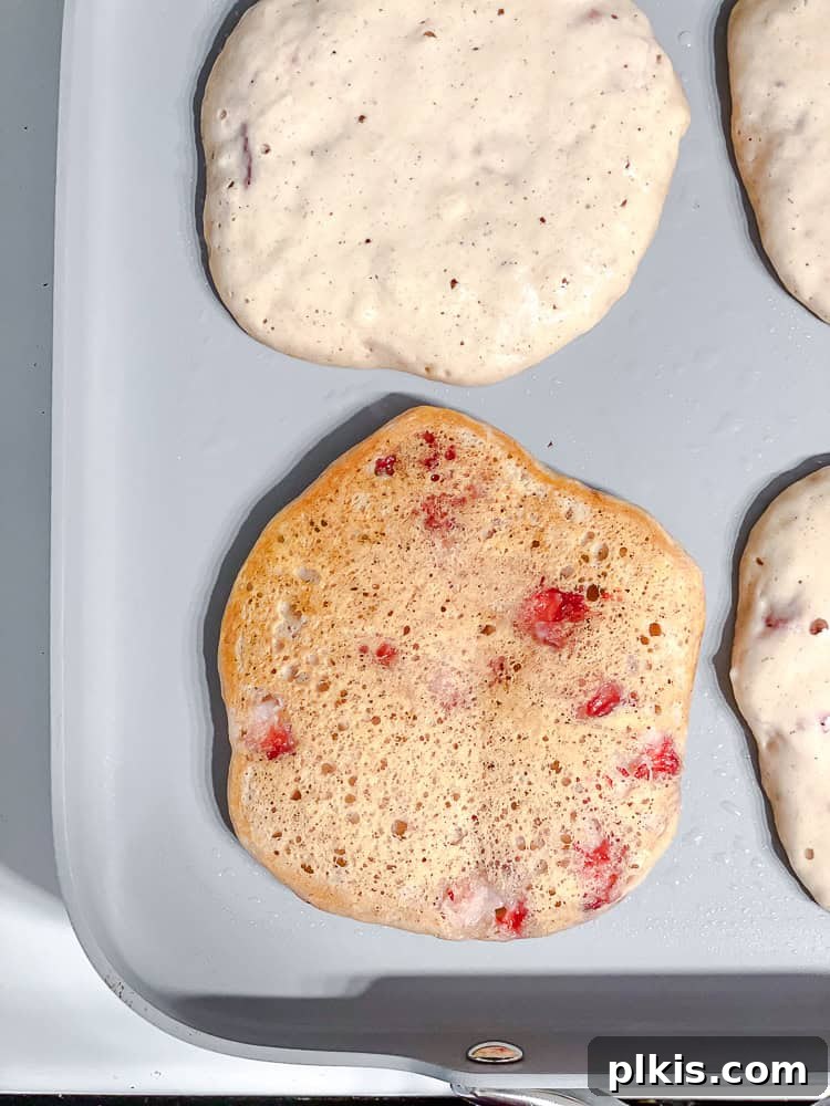 process shot showing Strawberry Pancakes [Eggless & Dairy-Free] cooking on pan