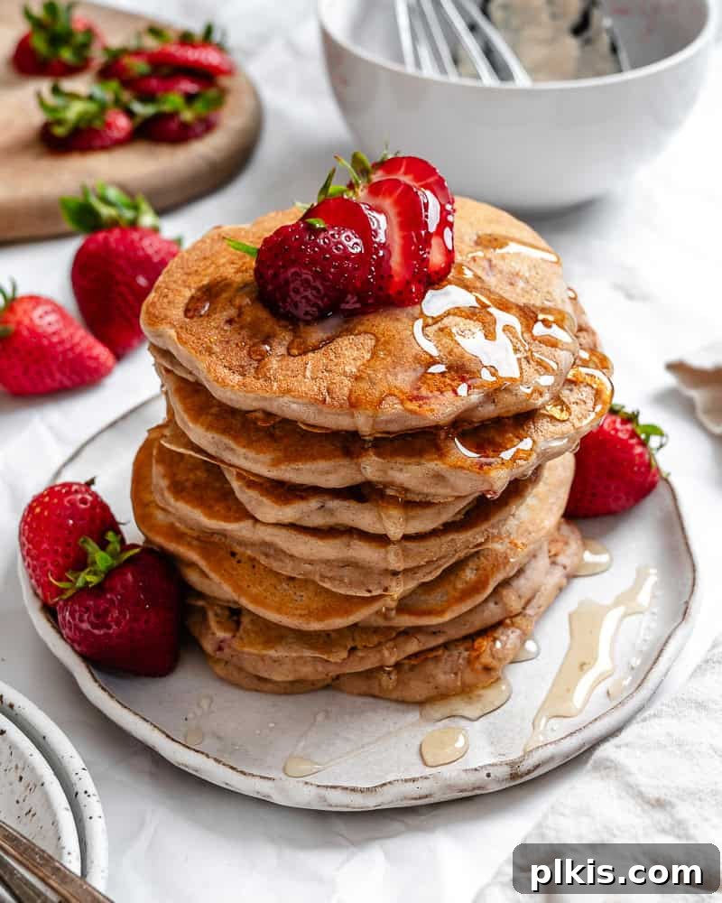 completed Strawberry Pancakes [Eggless & Dairy-Free] plated with fresh strawberries and syrup