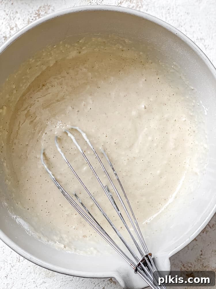 Golden Mango Cloud Cakes 5 Close-up process shot of wet and dry pancake ingredients being gently mixed in a bowl.