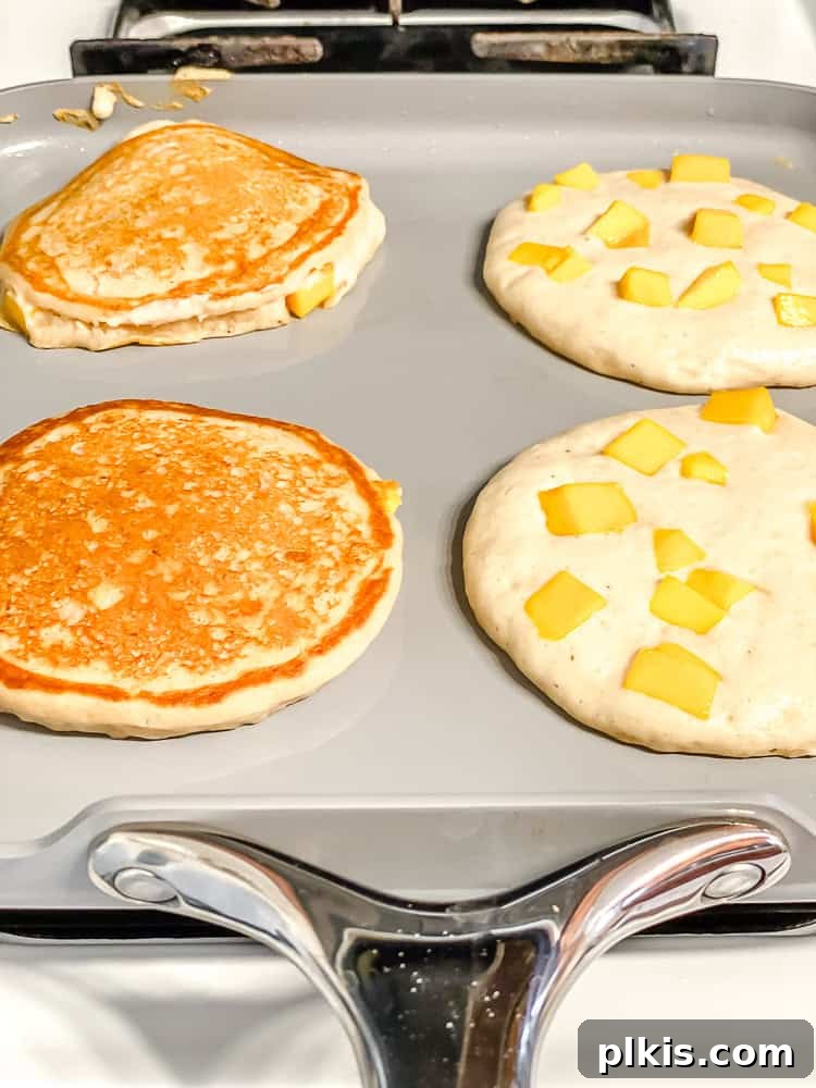 Golden Mango Cloud Cakes 7 Cooked fluffy mango pancake with golden brown edges and visible mango pieces.