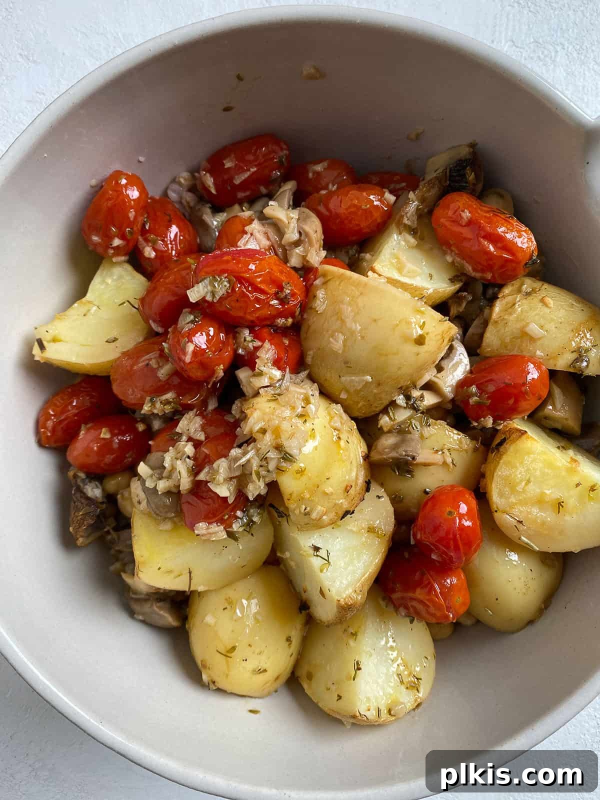 Process of mixing roasted vegetables and cooked farro together in a large bowl