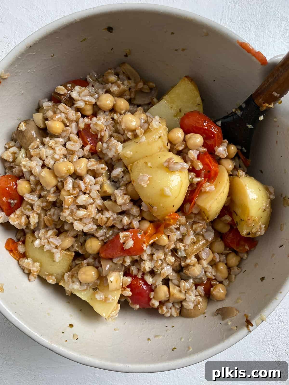 Process of mixing all ingredients for Easy Farro Recipe with Roasted Vegetables in a bowl, showing a well-combined dish